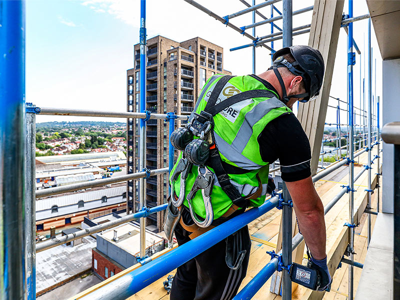 Man in PPE on scaffold on a high rise building doing cladding remediation.